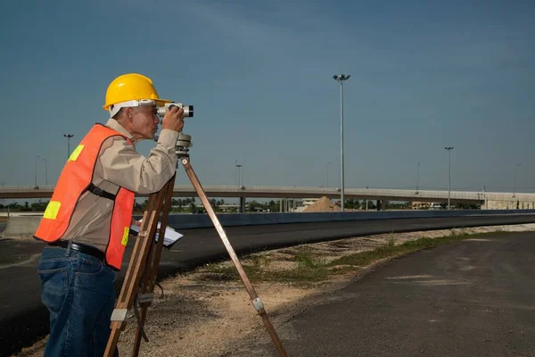 在道路建筑工地处理经纬仪设备的工程师或测量师 图库照片