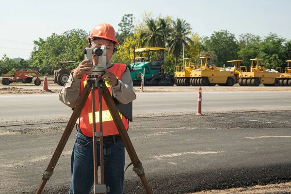 在道路建筑工地处理经纬仪设备的工程师或测量师 免版税图库图片