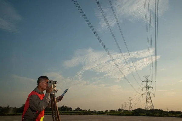 Theodolite Berendezéssel Dolgozó Mérnök Vagy Földmérő Nagyfeszültségű Háttérrel Rendelkezik Naplementekor Jogdíjmentes Stock Fotók