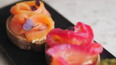 bright, juicy bruschetta from red fish and greens. delicious red fish, beautifully laid on fresh bread and seasoned with spices. haute cuisine. French cuisine. close-up. bright colours. juicy shots of french cuisine