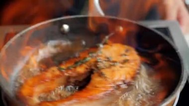 excellent grilled fish steak. French cuisine. the chef pours aged rum into a hot frying pan with a nice piece of meat. fire blazes in a frying pan. masterly roasting, delicious fish saik. alcohol evaporation