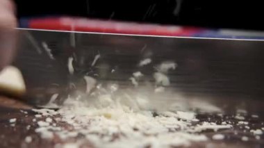 Aşçının bıçağının hareketiyle, boylamsal çipler küçük kırıntılar halinde kesilmiş. kaba kesim. Karanlık arka plan. Şef bıçağı. Cipsler. Ekmek kırıntılarına dönüşürler.. 