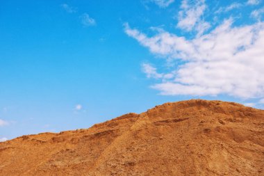 Büyük endüstriyel kum yığını. Mavi gökyüzüne karşı inşaat ve yol yapımında kullanıma hazır.