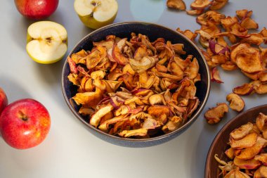 Ev yapımı kurutulmuş organik elma, dilimlenmiş, gri bir arka planda, bir tabakta.