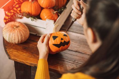 Kız balkabağını bıçakla kesiyor.