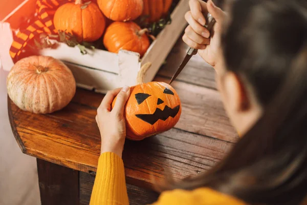 Kız balkabağını bıçakla kesiyor.