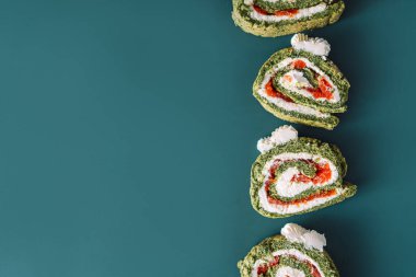 Cyan arka planda ıspanaklı ve kırmızı balıklı pürüzsüz rulo dilimler