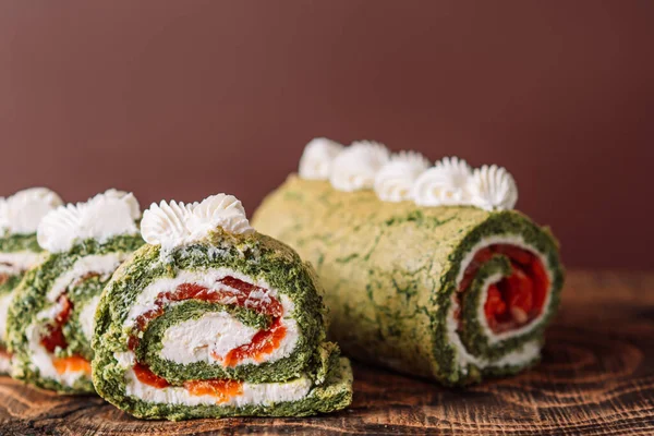 Tahta masada ıspanaklı ve kırmızı balıklı dilimlenmiş rulo.