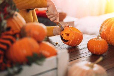 Bayram için hazırlanan kız bıçakla balkabağının gözlerini oyar. Jack-o-fener yapmak