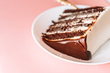 Yuvarlak tabakta küçük çatallı bir parça çikolatalı kek..