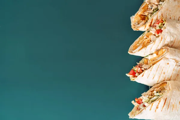 Cyan arka planda dört shawarma kesiti.