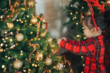 Pijamalı bir kız Noel ağacına takılır..