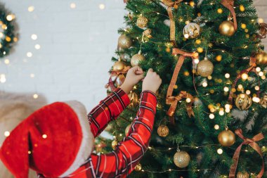 Pijamalı çocuk Noel ağacında takılıyor..