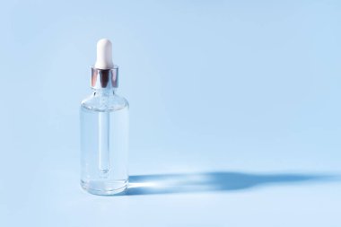 Mavi arka planda şeffaf sıvı pipetli cam kavanoz.