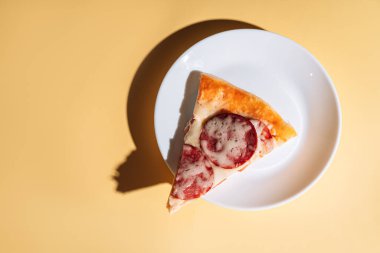 Beyaz tabakta sosisli bir dilim pizza.