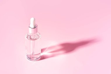 Pembe arka planda şeffaf sıvı pipetli cam kavanoz.
