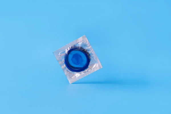 Blue condom in transparent package on blue background — ストック写真