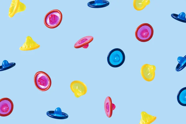 Falling multi-colored condoms on blue background — Photo