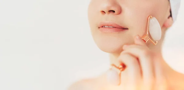 A menina faz massagem facial com rolo de pedra — Fotografia de Stock