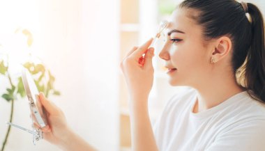 Aynalı kız taş silindirle yüz masajı yapıyor.