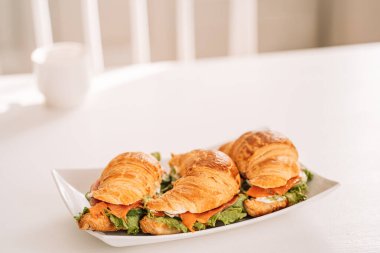 Kare tabakta kırmızı balıklı kruvasanlar.