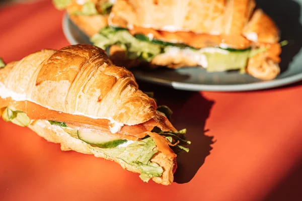 Сэндвич с красной рыбой и салатом на оранжевом столе — стоковое фото