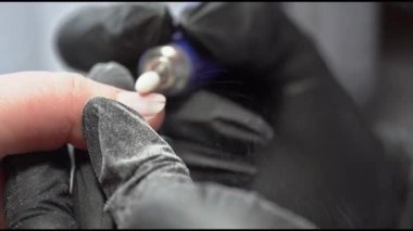 Manikürcü elektrikli bir dosya ile çivileri işliyor