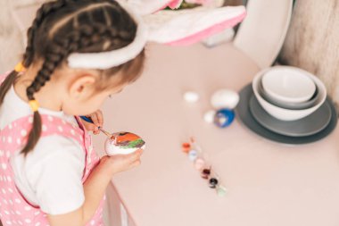 Tavşan kulaklı çocuk Paskalya için renkli yumurta hazırlıyor.