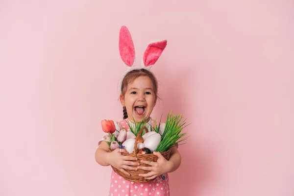Ребенок с корзиной в руках на розовом фоне — стоковое фото