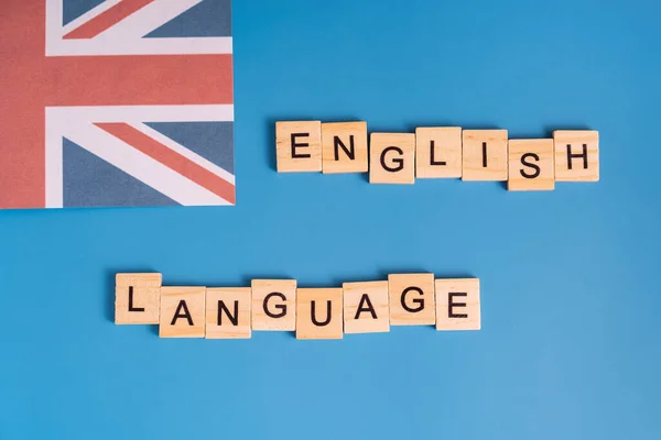 Język angielski z literami obok brytyjskiej flagi na niebieskim tle — Zdjęcie stockowe