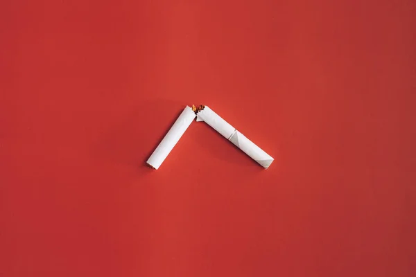 Kırık sigaranın yarısı kırmızı arka planda. — Stok fotoğraf