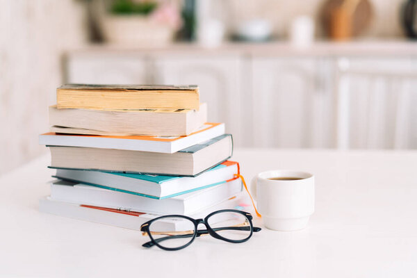 Пачка книг со стаканами и чашкой кофе, стоящих на столе