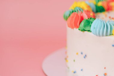 Pembe arka planda renkli kremalı beyaz pastanın arka planı