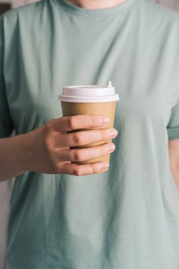 Girl in green t-shirt holding glass of hot coffee