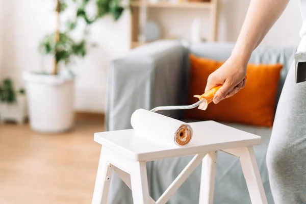 Girl paints table with white paint stepladder with roller — Stockfoto