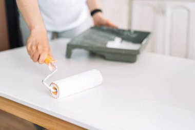 Tahta masayı beyaza boyuyor.