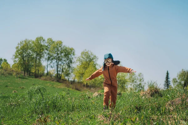 Boy in pilot suit runs on green grass in the open air — Foto de Stock