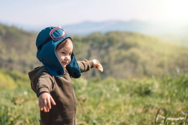 Kılavuz kıyafetli, açık havada kollarını açmış bir kız.