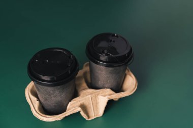 Yeşil arkaplanda duran tek kullanımlık bardaklar