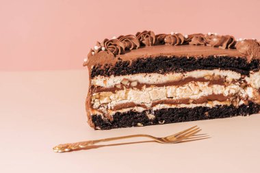 Pembe arka planda çatalın yanında dilimlenmiş pastanın yarısı.