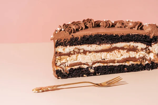 Pembe arka planda çatalın yanında dilimlenmiş pastanın yarısı.