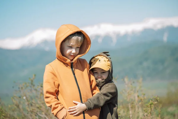 Brother and sister in overalls stand in the field against the mountains — Foto de Stock