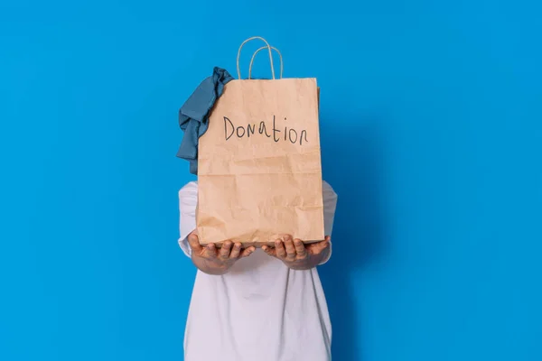 Girl holding paper bag with clothes in front of her for donation.