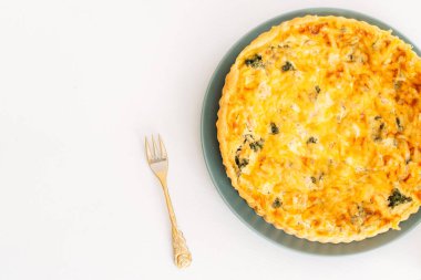 İçinde tavuk turtası ve altın çatal olan açık bir kutu beyaz bir masada duruyor..