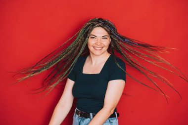 Kırmızı arka planda çok renkli örgülü bir kız..