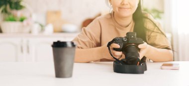 Kız beyaz masada oturan kamerayı bir fincan kahveyle ayarlıyor..