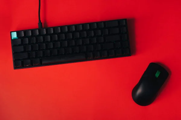 Computer gaming mouse and keyboard against red background.