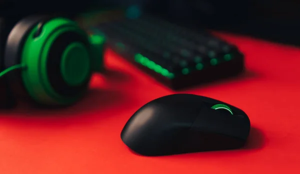 Computer gaming mouse and keyboard and green hedset on red background.