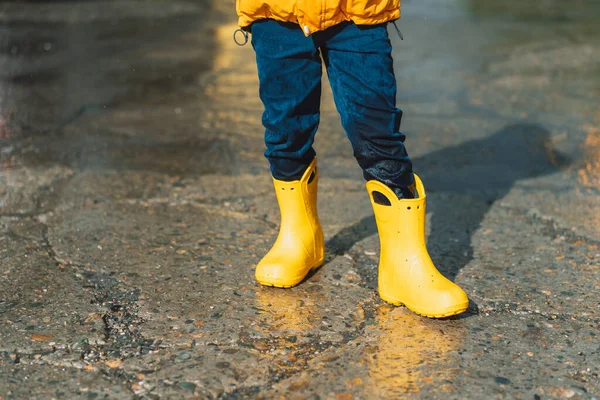 Boy in yellow rubber boots and wet jeans.
