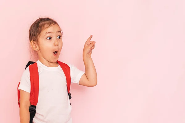 Surprised Little Girl Red Briefcase Points Her Finger Pink Background — Zdjęcie stockowe
